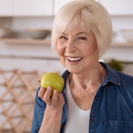 Happy senior woman preparing to bite into apple