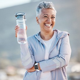 Woman smiling with a water bottle on an outdoor hike