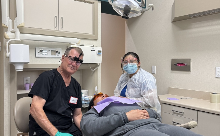 Two young individuals standing and smiling in a dental office hallway