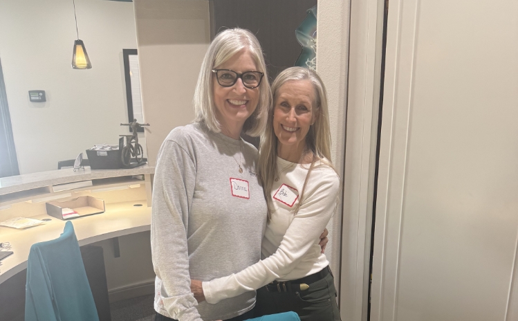 Dental professional standing with a smiling patient in a treatment room