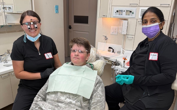 Four dental team members smiling together in a treatment room