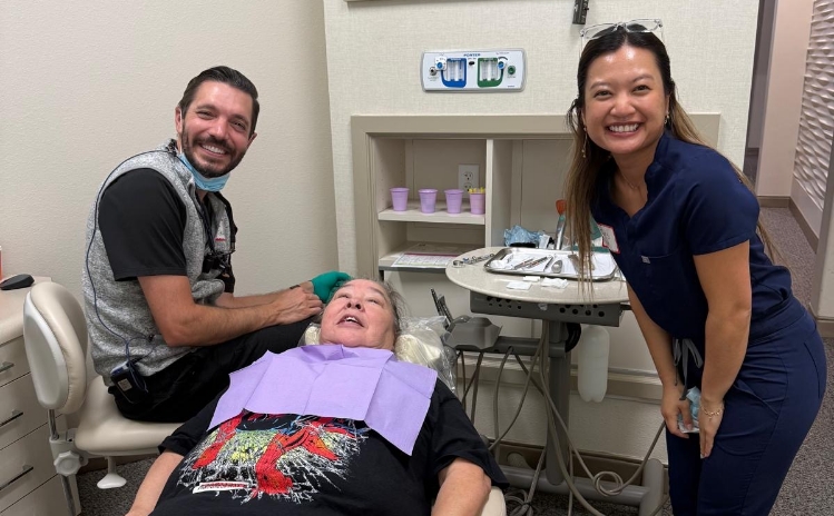 Two dental professionals holding trays of instruments and smiling