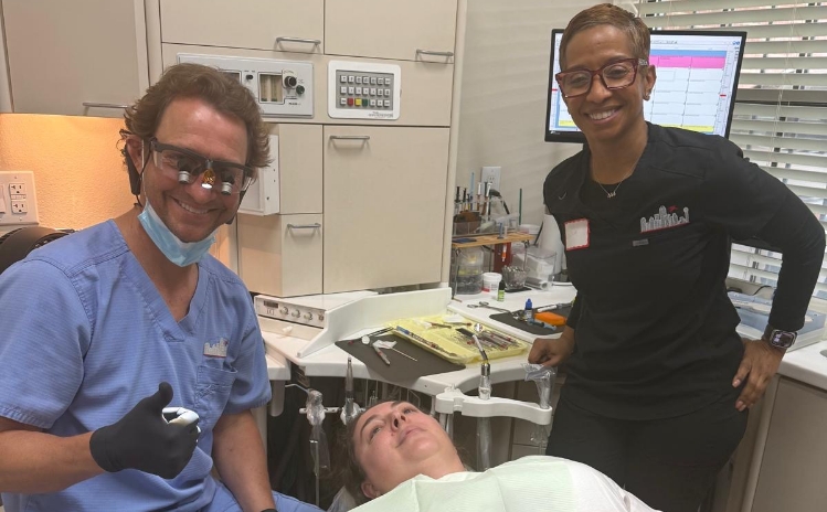 Two dental team members sitting together and smiling