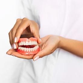 Closeup of dentist holding dentures in Mesquite