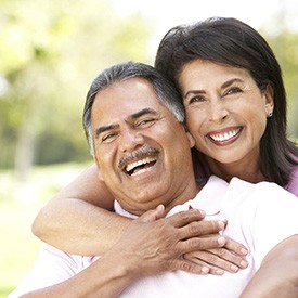 Smiling couple with dentures in Mesquite outdoors in a park