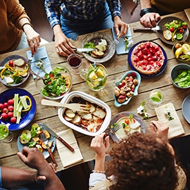 Bird’s eye view of group of people sitting around wooden table enjoying a variety of foods