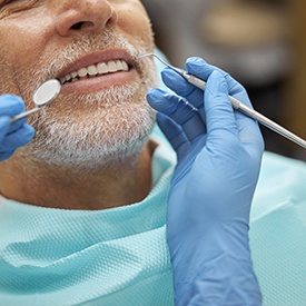 Nose-to-chest view of man with gray beard about to have dental exam
