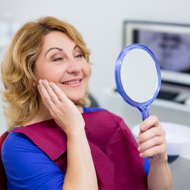 Woman admiring her smile after getting dental implants 
