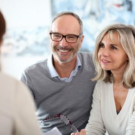 Smiling couple listening to dentist about dental implants