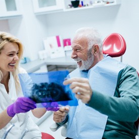 Excited man smiling at dentist after getting dental implants 
