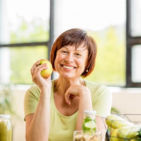 Smiling woman with dental implants holding an apple