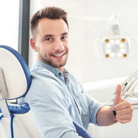 smiling man giving thumbs up in the dental treatment chair