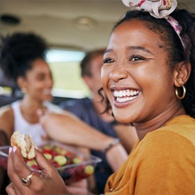 person smiling and eating a sandwich and fruit