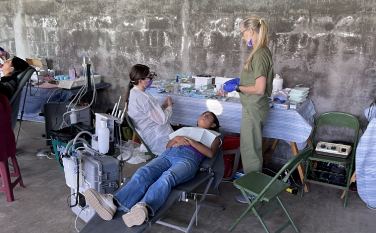 Three women smiling together during a community dental mission event