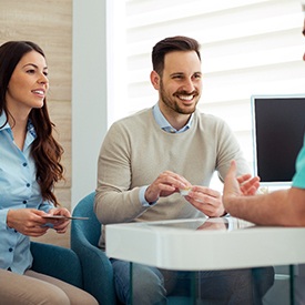 Couple smiling while talking to dentist in their office