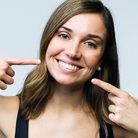 Woman pointing to teeth after teeth whitening in Mesquite