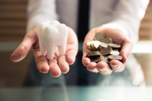 A person holding change and a model of a tooth.