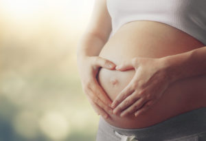 Pregnant woman making a heart shape over her belly