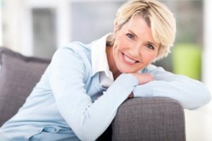 Woman leaning on the arm of a couch smiling