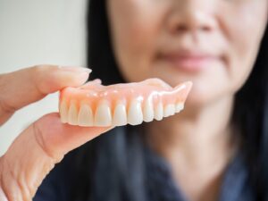 Woman holding denture up for close-up.